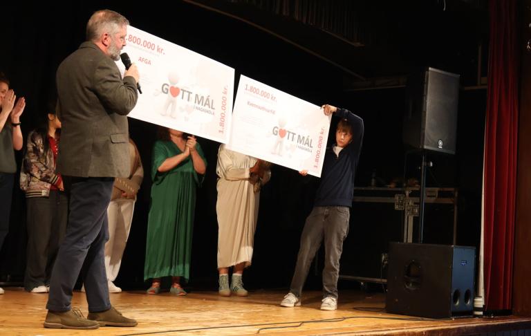 Principal and student hold checks with fundraising money in front of students