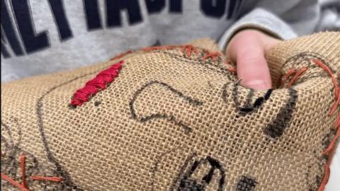 Nemandi saumar andlitsmynd í striga.